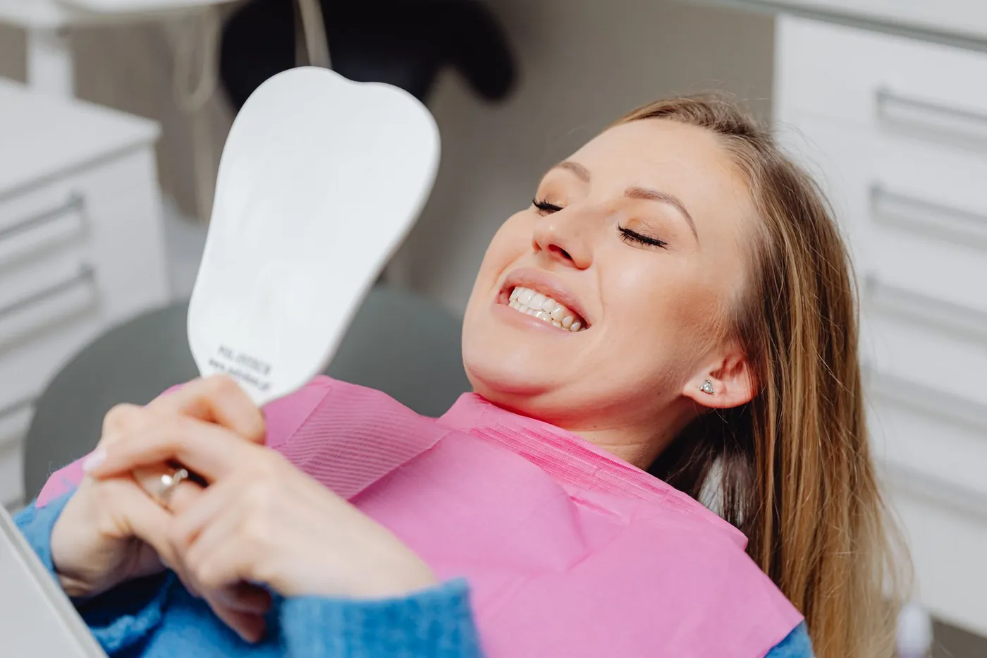 Paciente sonriendo en el sillón dental con un espejo